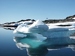 Голубые айсберги самой причудливой формы и их бирюзовые отражения в зеркальной воде на фоне прибрежного заснеженного пейзажа с оттаявшими скальными породами формируют незабываемый калейдоскоп бело-голубой Антарктики.